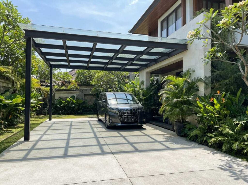 Desain jenis kanopi kaca tempered untuk rumah Denpasar modern dengan struktur rangka besi galvanis hitam minimalis dan kokoh.
