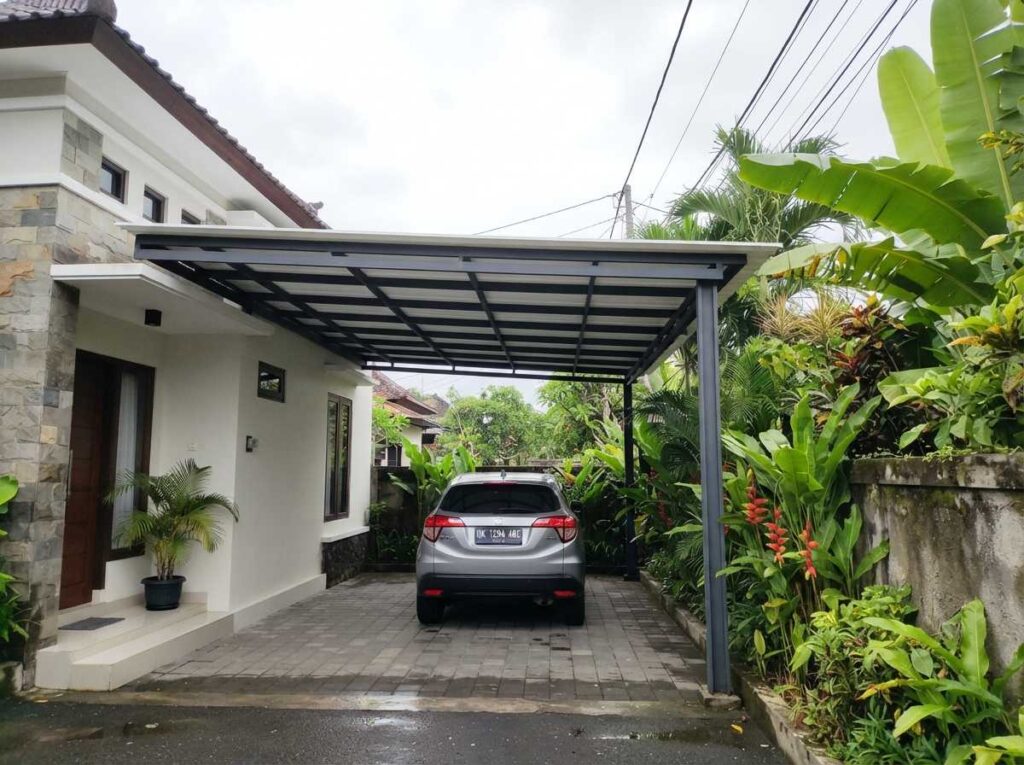 Pemasangan kanopi Bali dengan struktur rangka besi hollow galvanis tebal dan atap uPVC yang rapi untuk garasi rumah.